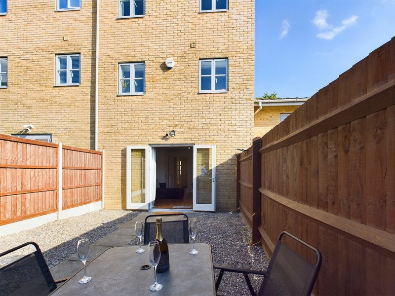 Brick townhouse with patio area, wooden fencing, and patio furniture