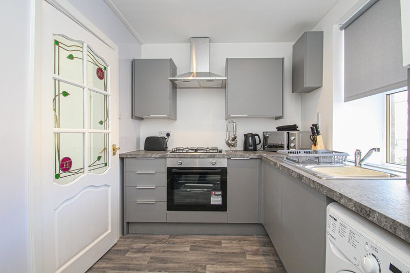 Modern kitchen with gray cabinetry, gas hob, built-in oven, and granite countertops