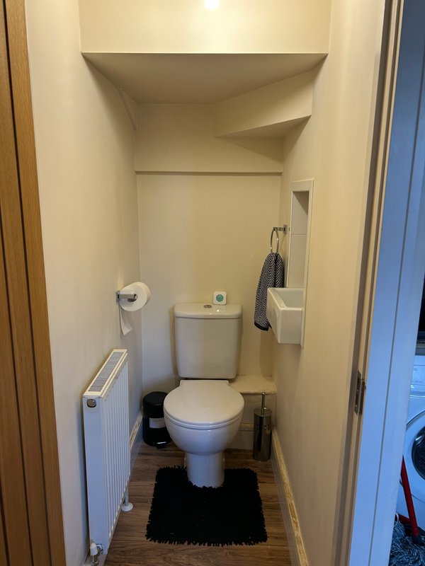 Small bathroom with toilet, sink, radiator and black bath mat