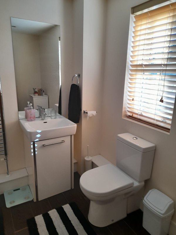 Compact bathroom with white sink vanity, toilet, mirror and window with wooden blinds