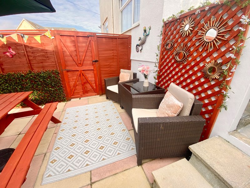 Outdoor patio with wicker seating, geometric patterned rug, red gates and decorative wall panels