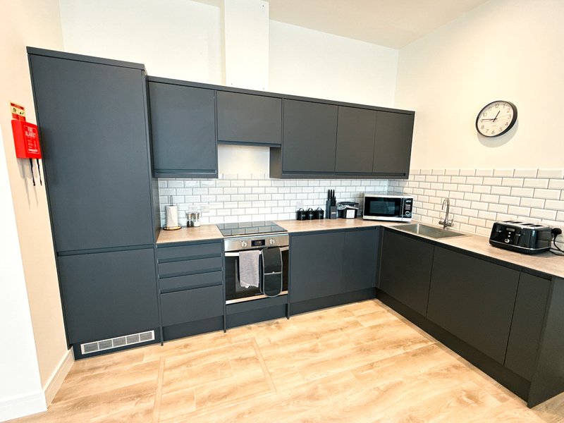 Modern kitchen with dark cabinetry, white subway tile backsplash, wooden worktops and stainless steel appliances