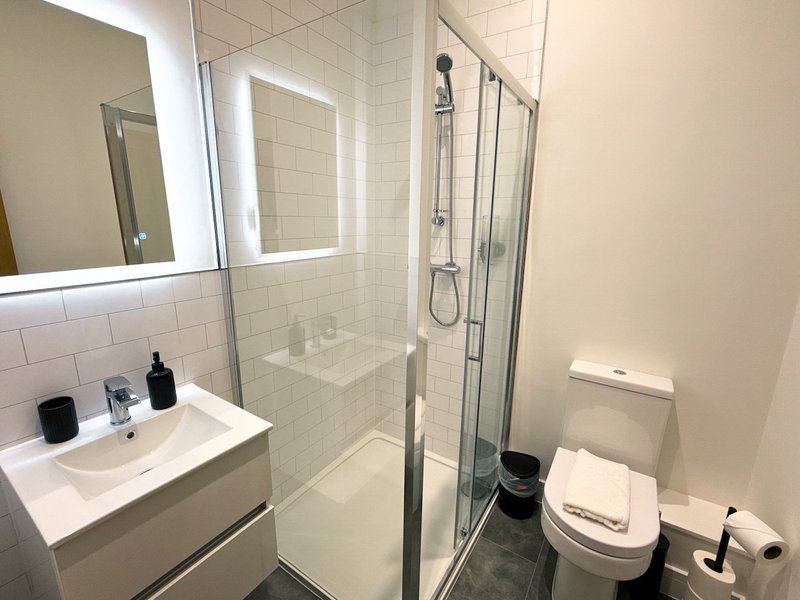Modern bathroom with white subway tile, glass shower enclosure, white vanity and toilet