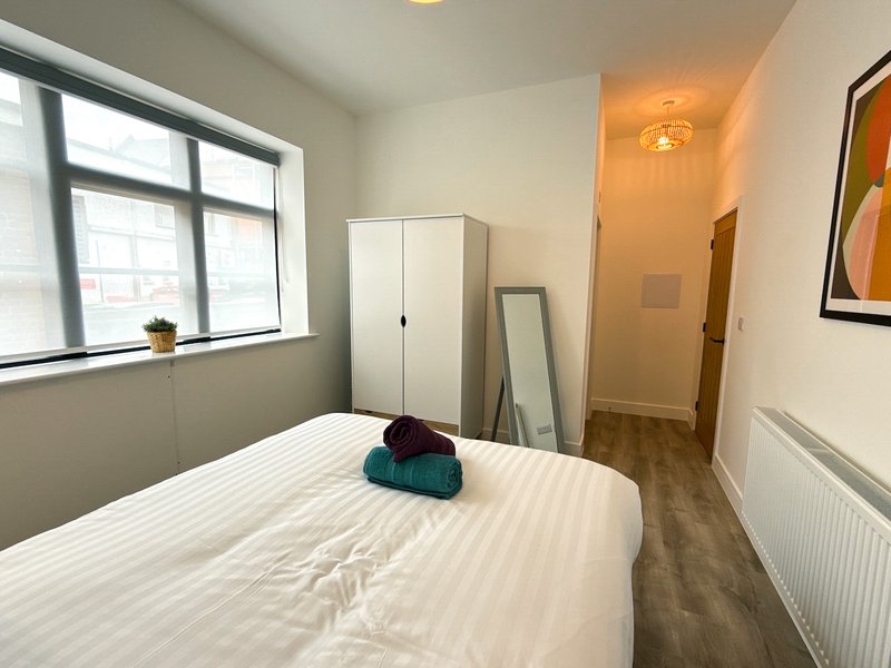 Bedroom with double bed, wardrobe, window with natural light, and wooden flooring