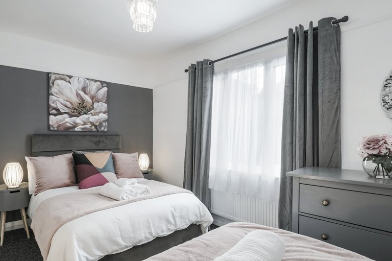 Modern bedroom with double bed, grey feature wall, grey curtains and bedside lamps