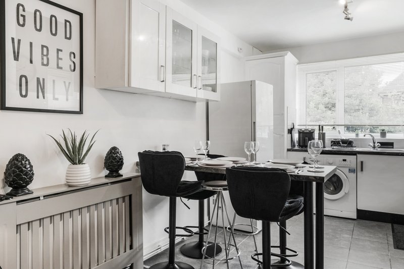 Modern kitchen with dining counter, black chairs, white cabinetry and appliances