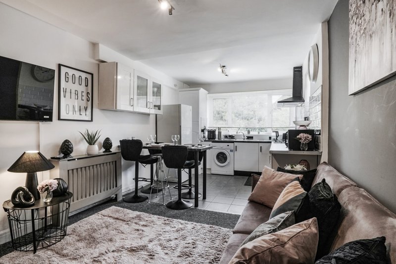Modern open-plan kitchen and living area with dining table, sofa, and decorative wall art