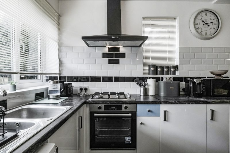 Modern kitchen with white cabinetry, black and white tile backsplash, gas cooktop, and stainless steel appliances