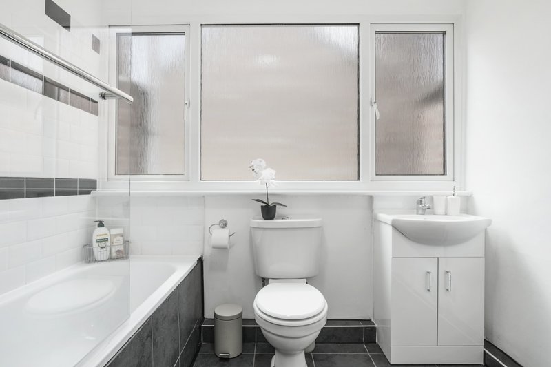 Modern bathroom with white suite, bathtub, toilet, sink and mirrored cabinet