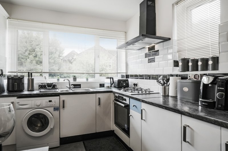 Modern kitchen with white cabinetry, black countertops, stainless steel appliances and window