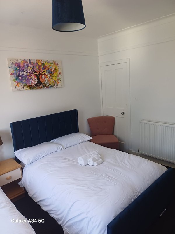 Bedroom with double bed, navy headboard, colorful abstract wall art, pendant light