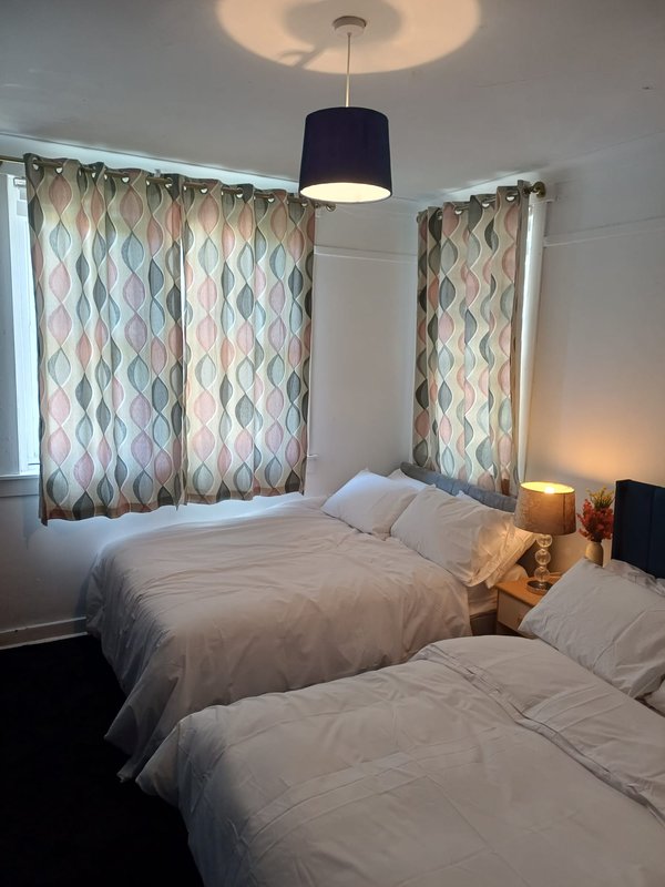 Bright bedroom with two single beds, patterned curtains, pendant lamp and bedside tables