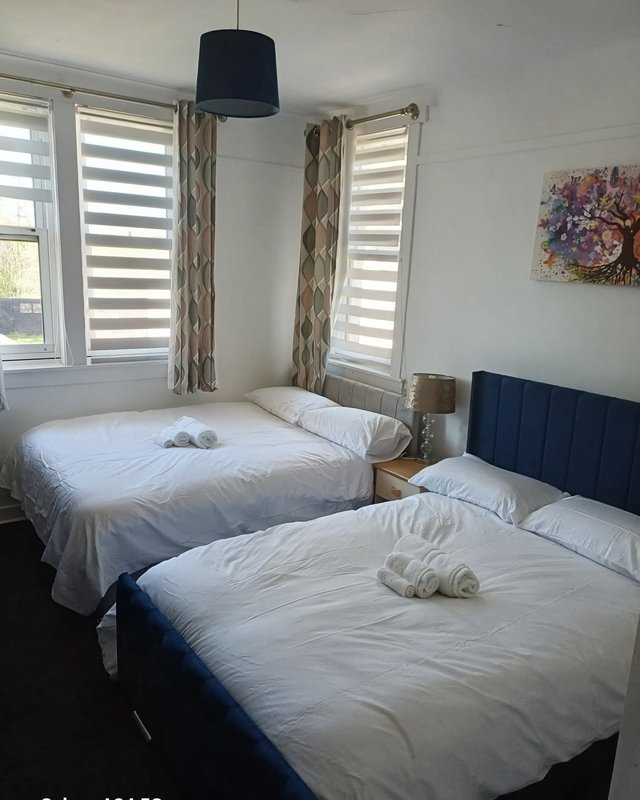 Bright twin-bedroom with two beds, navy headboards, striped curtains and pendant lamp