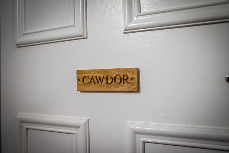 White wall with wooden door sign reading 'CAWDOR' between two white-framed doors