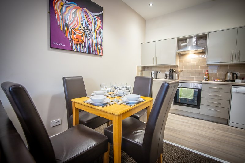 Modern kitchen-diner with yellow table, grey chairs, and fitted kitchen units