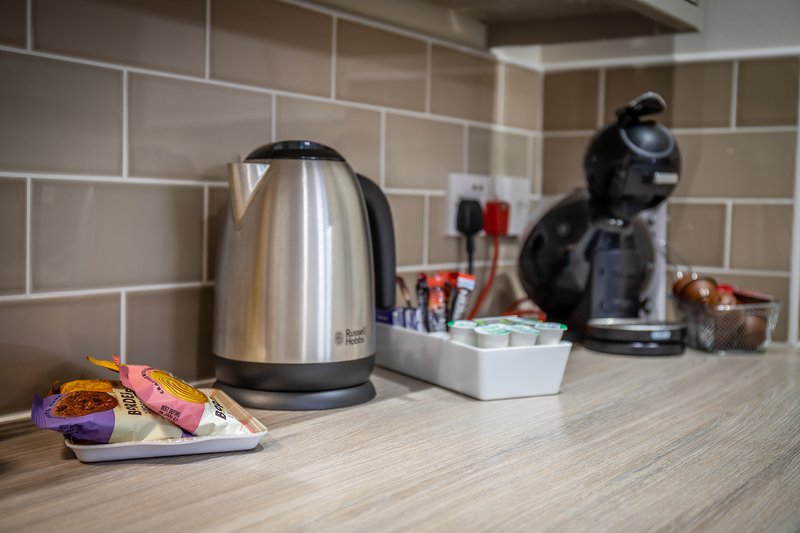 Kitchen counter with kettle, coffee maker, and breakfast items on tile backsplash