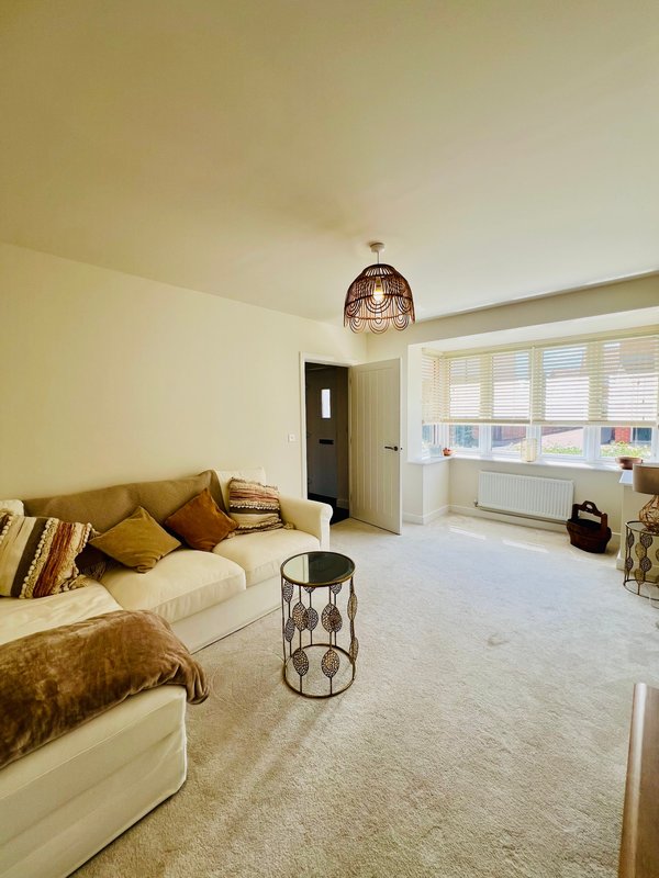 Bright living room with cream sofa, mustard cushions, pendant light and window seat