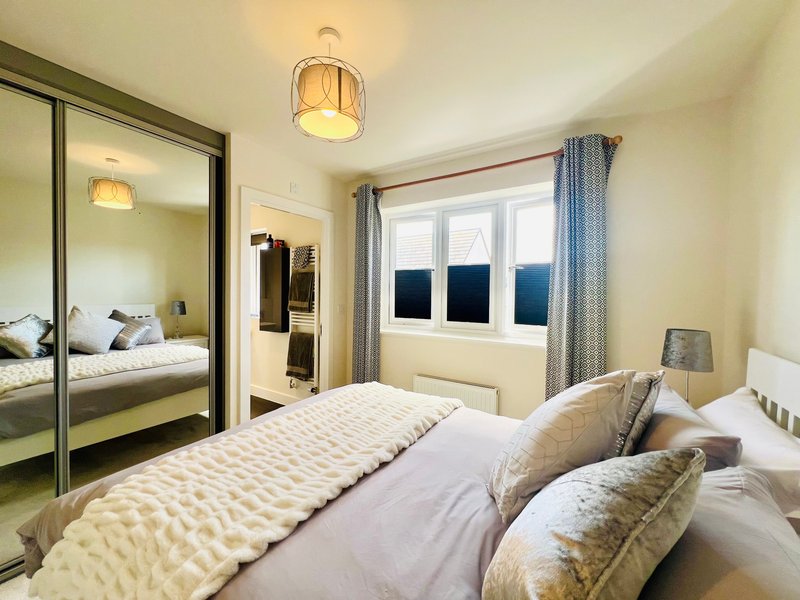 Bright bedroom with double bed, mirrored wardrobe, window with blue curtains, pendant lighting