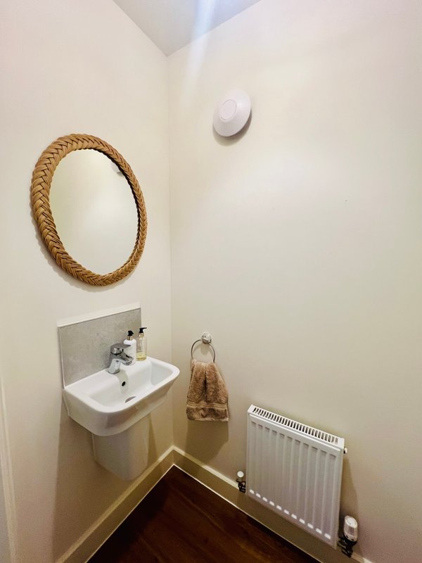 Compact bathroom with wall-mounted sink, rope-framed mirror, radiator and towel rail