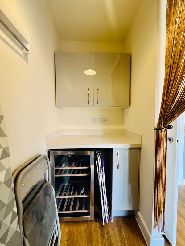 Compact bathroom with mirror cabinet, sink, wine cooler, and wooden flooring