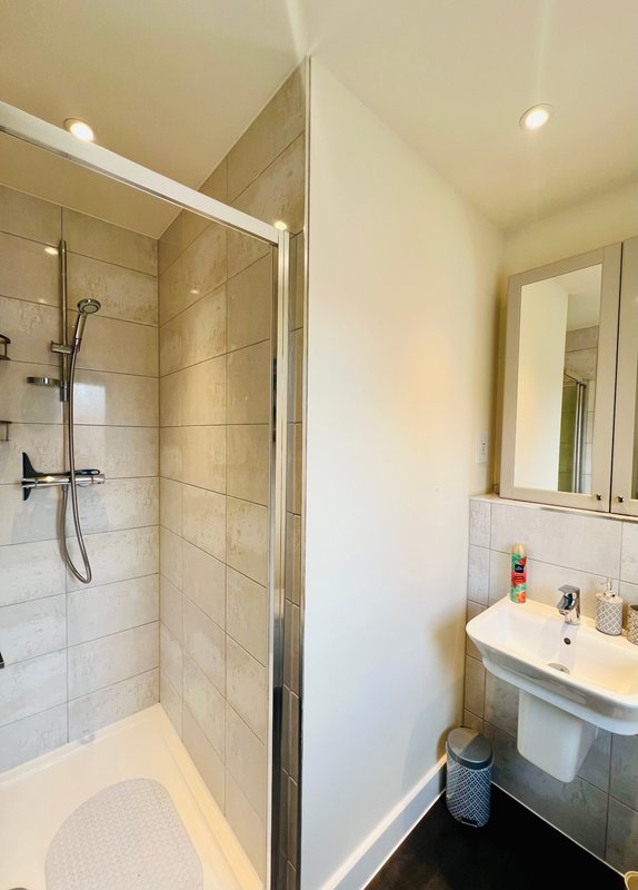 Modern bathroom with walk-in shower, white basin, and heated towel rail