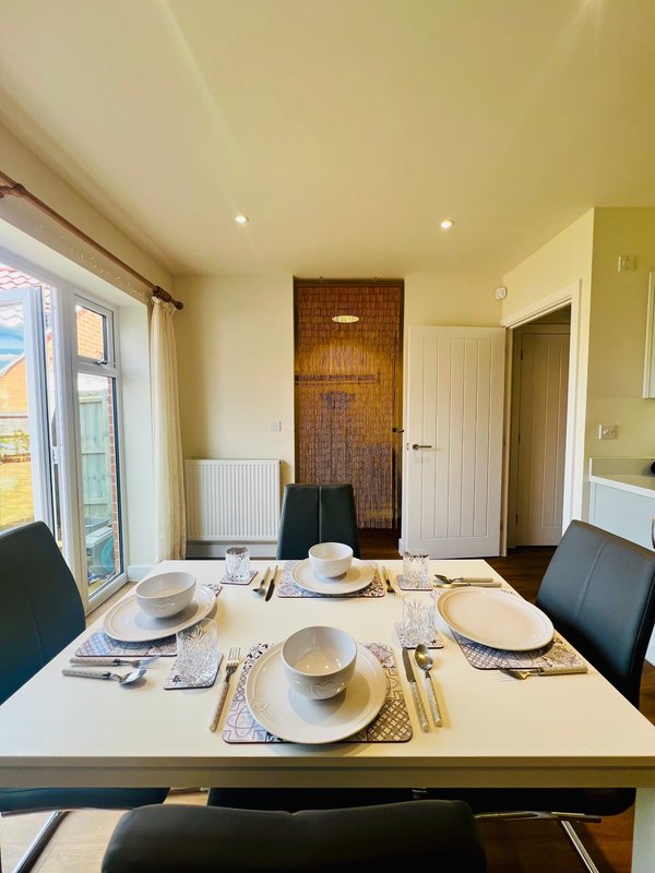 Dining room with set table, black chairs, glass doors and wooden wall feature
