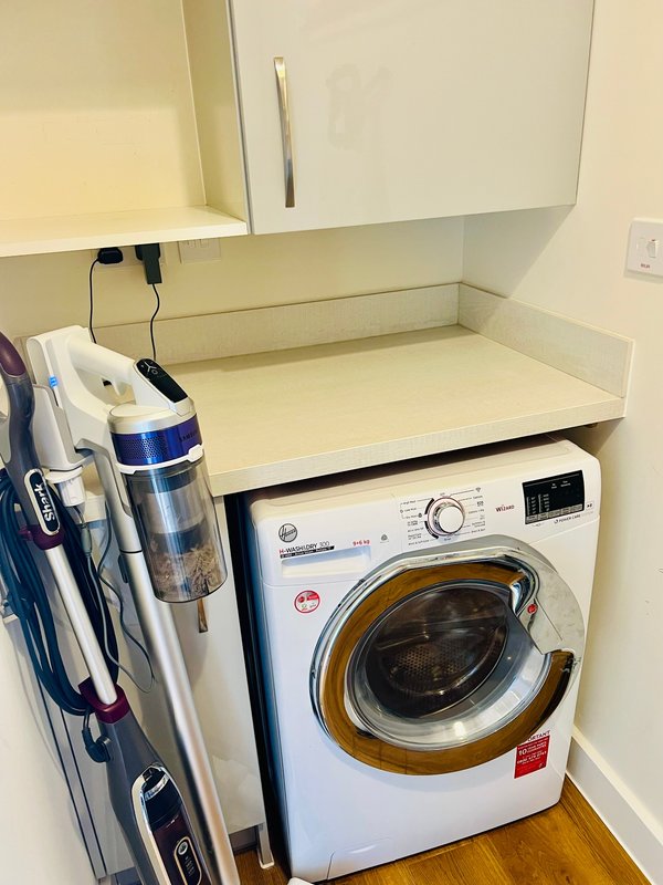 Laundry room with front-load washing machine, storage shelves, and cleaning supplies