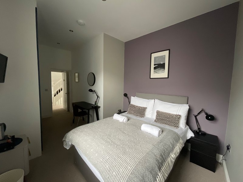 Bedroom with double bed, purple accent wall, bedside tables and mirror