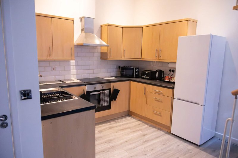 Modern kitchen with wooden cabinets, stainless steel appliances, white tile backsplash and island