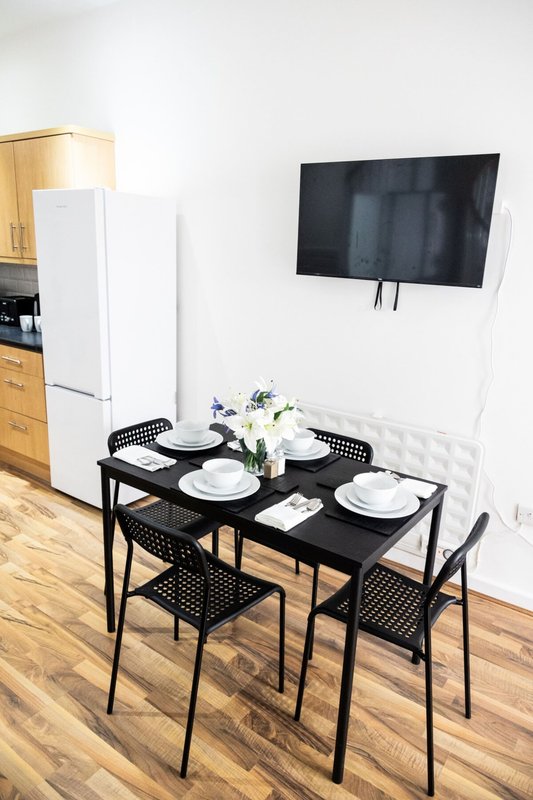 Modern dining area with black table, chairs, place settings, and wall-mounted TV