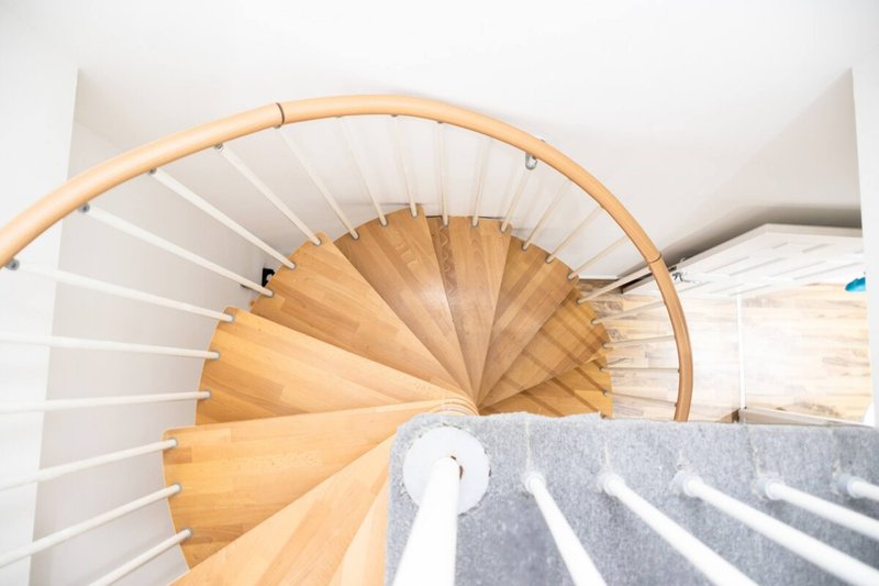 Overhead view of modern spiral staircase with wooden treads and white walls