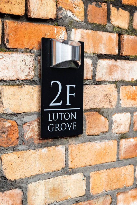 Brick building exterior with mounted address plaque reading 2F Luton Grove
