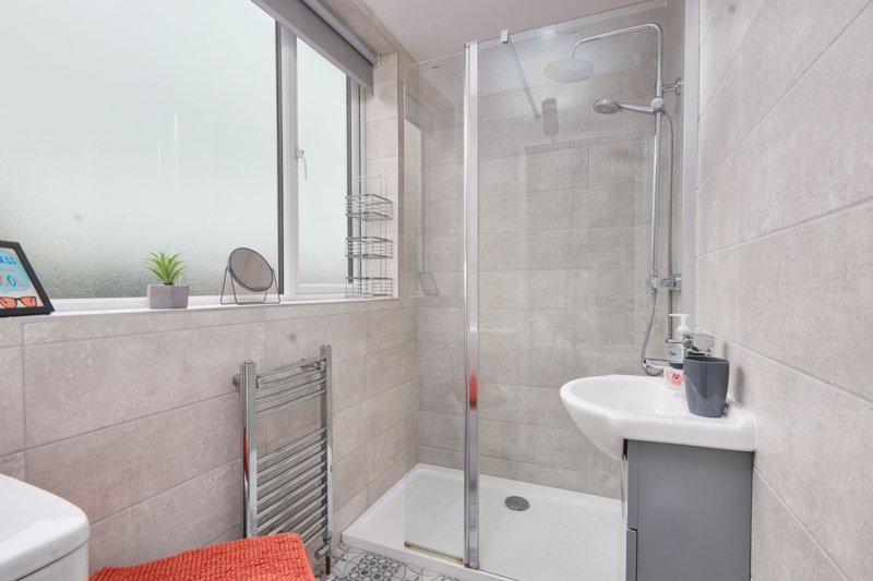 Modern bathroom with walk-in shower, white basin, heated towel rail and window