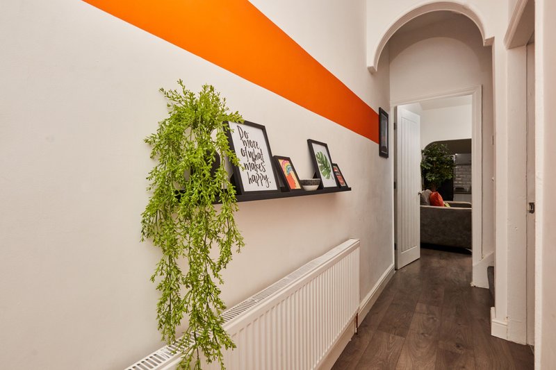 Hallway with orange accent stripe, floating shelf, trailing plant and wooden flooring