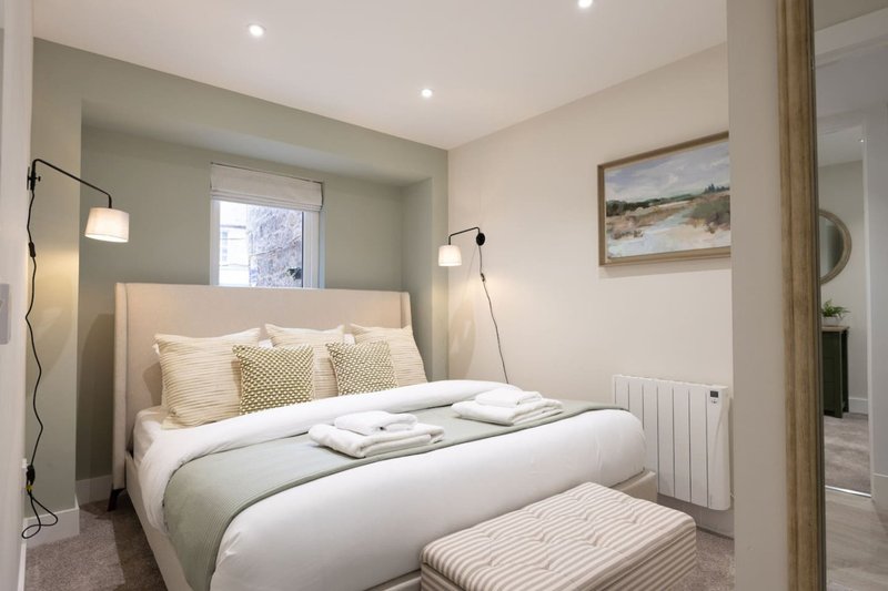Modern bedroom with double bed, cream bedding, pendant lamps, and neutral décor