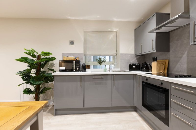 Modern kitchen with gray cabinetry, integrated appliances, yellow table and potted plant