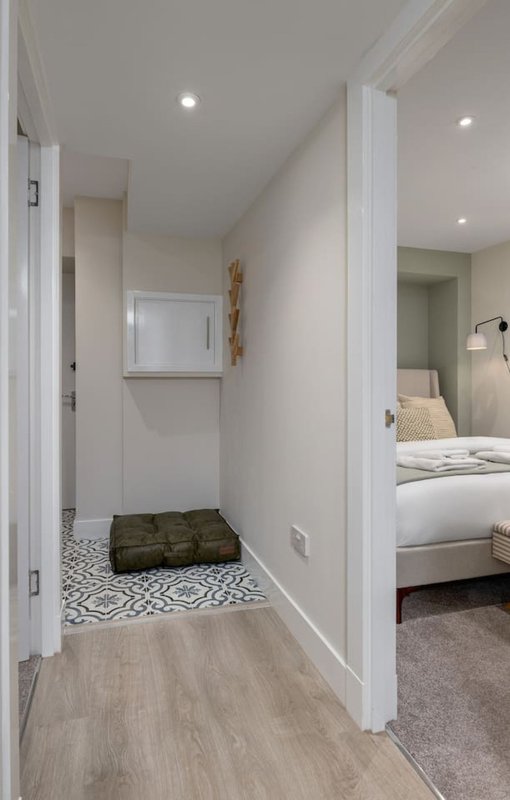 Hallway with white walls, recessed lighting, patterned floor tiles and bedroom view