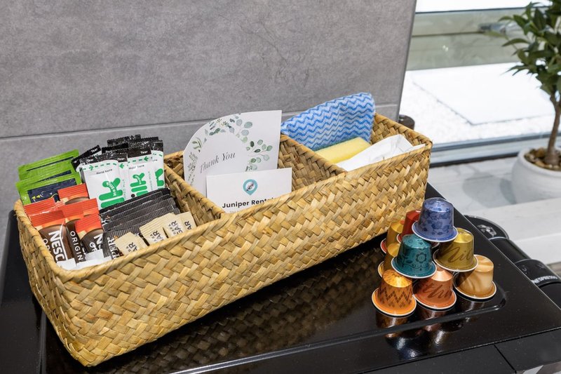 Kitchen counter with woven basket organizer holding toiletries, coffee pods, and supplies