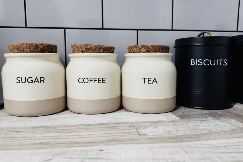 Kitchen counter with labeled storage jars for sugar, coffee, tea, and biscuits