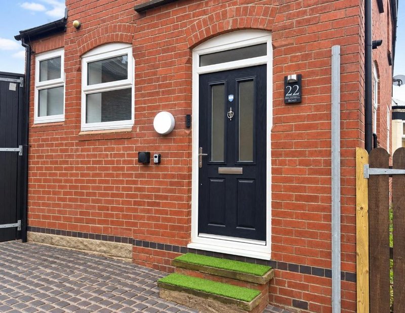 Red brick property exterior with black door, white window frames and entrance steps