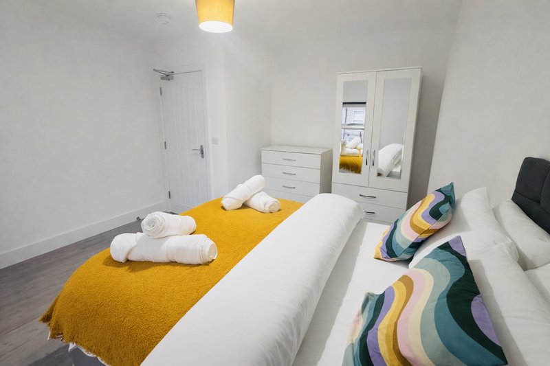 Modern bedroom with twin beds, yellow bedding, white furniture and mirrored wardrobe