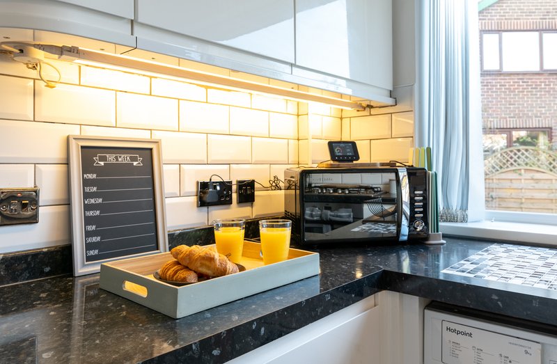 Modern kitchen with black countertop, subway tile backsplash, appliances and breakfast items on counter