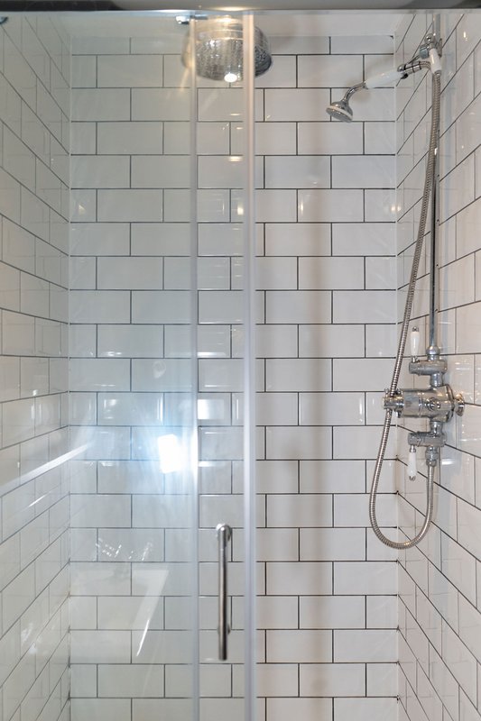 Modern shower enclosure with glass door, subway tile walls and chrome fixtures
