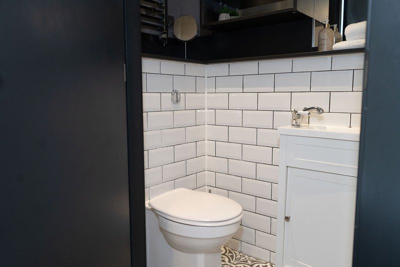 Bathroom with white subway tile walls, toilet, sink, and black vanity cabinet