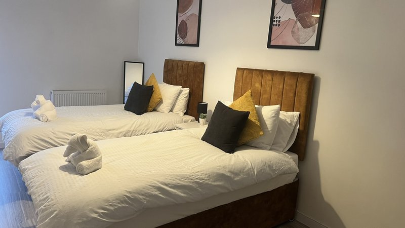 Bedroom with two single beds, wooden headboards, cream bedding and decorative pillows