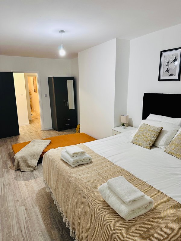 Bright bedroom with two beds, wooden flooring, white walls, and modern furnishings