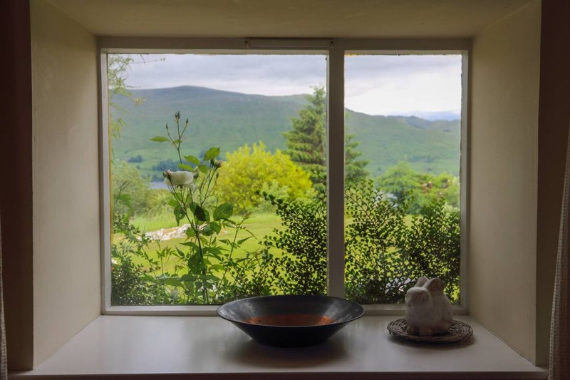 Modern windowsill with bowl and decorative object overlooking green valley and mountains