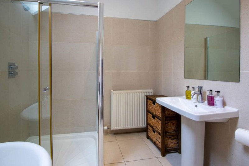 Modern bathroom with shower enclosure, pedestal sink, wooden vanity and mirror