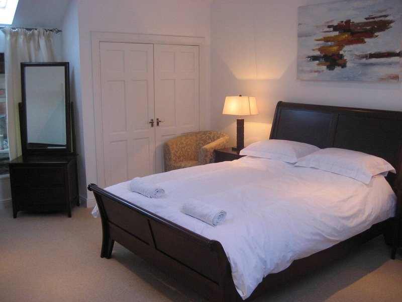 Bedroom with black bed frame, white bedding, lamp, mirror, and wardrobe doors