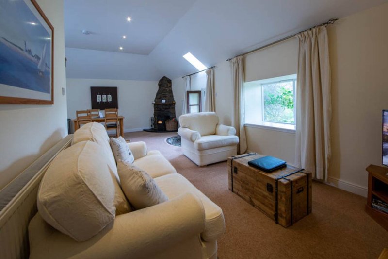 Spacious living room with cream sofas, wooden furniture, fireplace and large windows